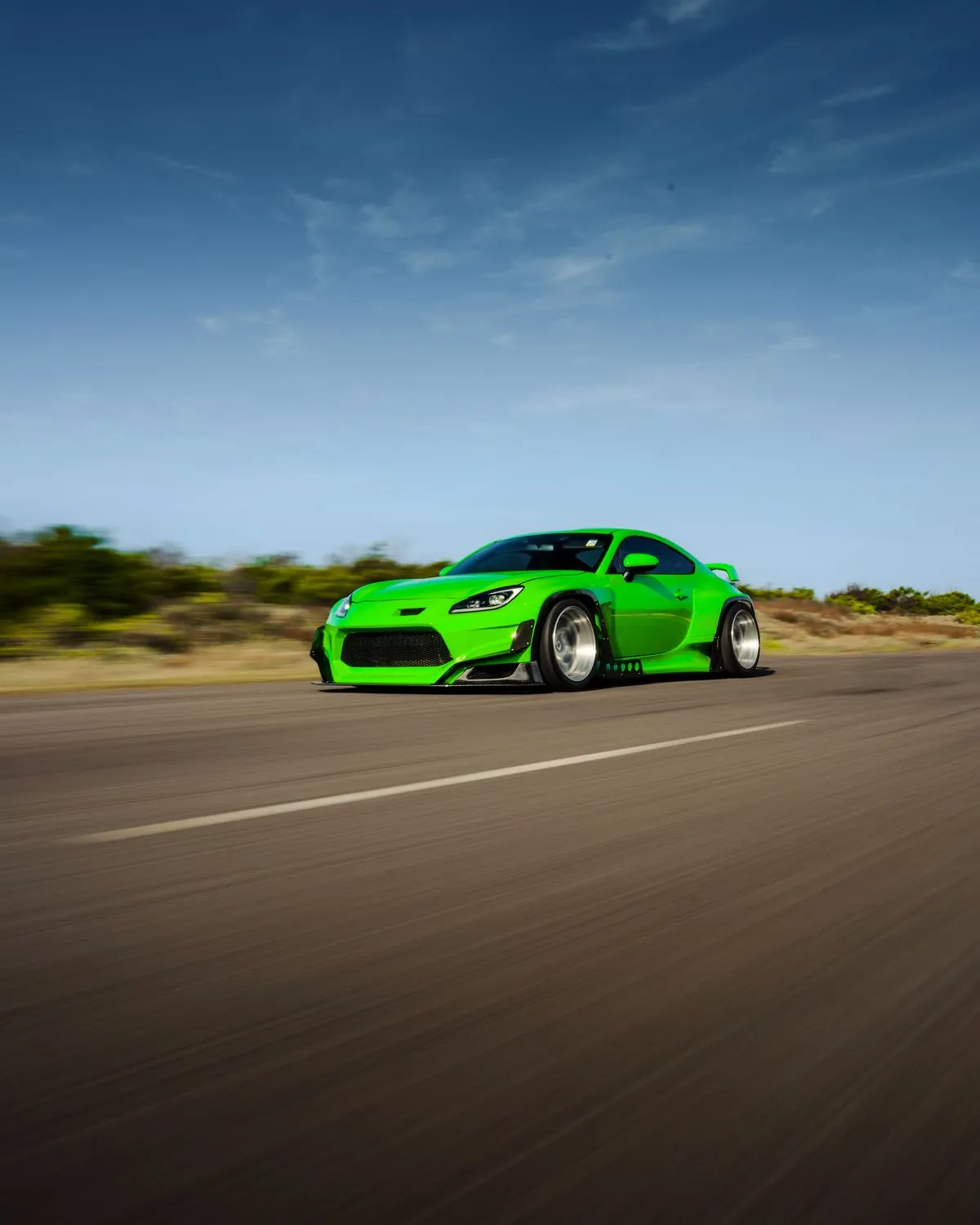 Green widebody on an open road, built by Passato Garage