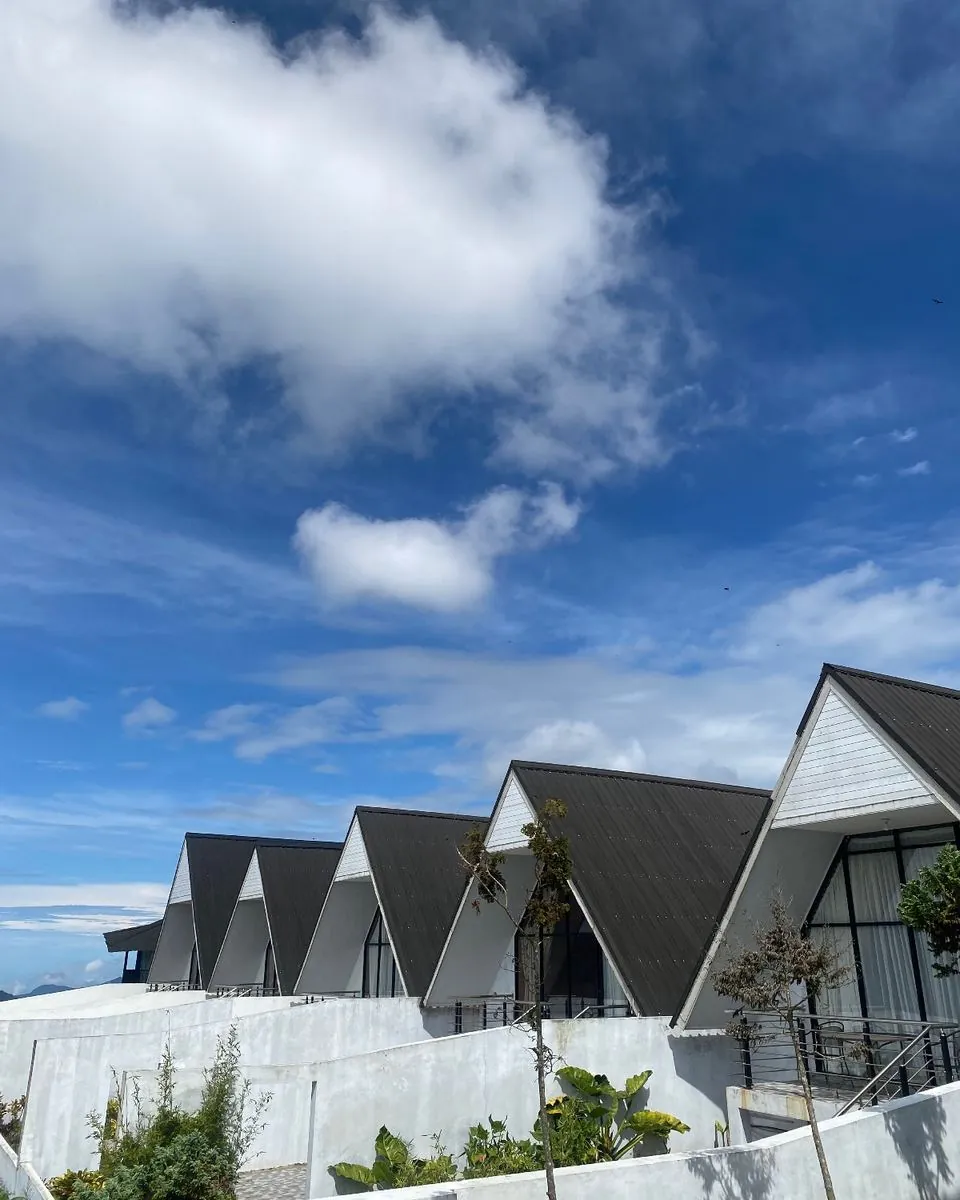 Cambai Hill A-frame cabins under a blue, cloudy sky