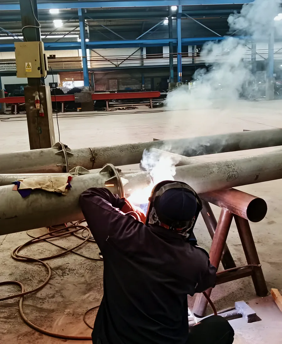 A welder joining steel pipe in the workshop