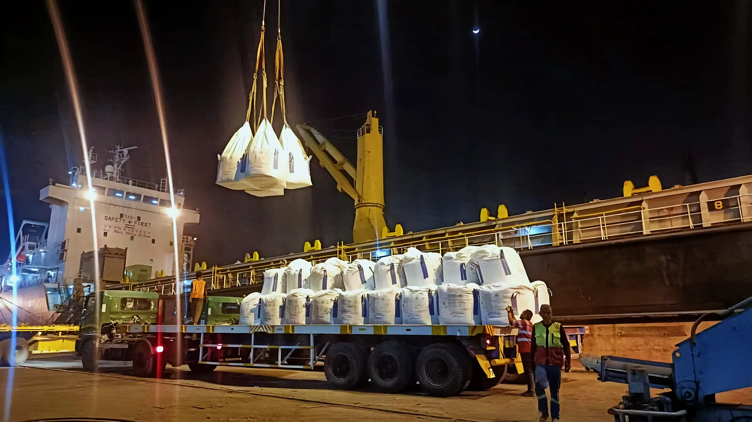 Bulk bags lifted onto a trailer truck at the port at night
