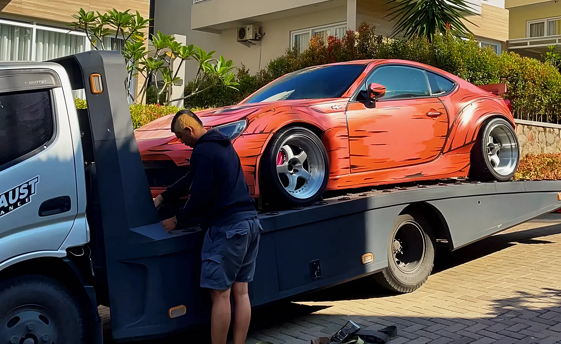A widebody car loaded onto a flatbed tow truck